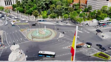 Manzaralı bir Plaza de Cibeles, İspanya 'nın Madrid kentinde ulusal bayraklar ve etkileyici mimari tasarımlarla çevrili çeşme kaplı bir anıta ev sahipliği yapmaktadır.