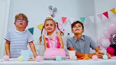 Genç bir kızın dilek tuttuğu bir doğum günü partisi sahnesi. Mumları üflerken, etrafında şapkalı iki çocuk alkışlıyor.