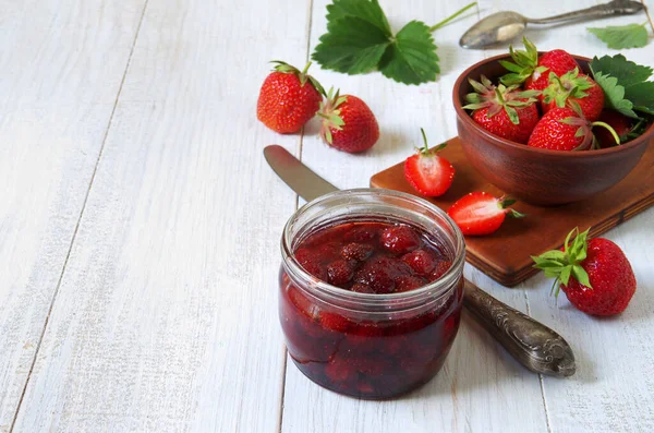 一罐草莓果酱放在白色木制桌子的背景上 成熟的浆果 — 图库照片