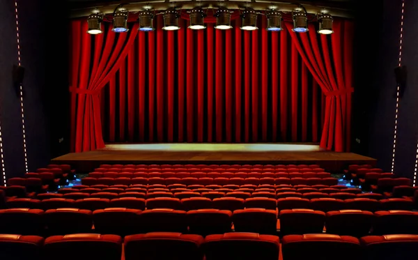 theater stage with red curtains and seats under spotlights