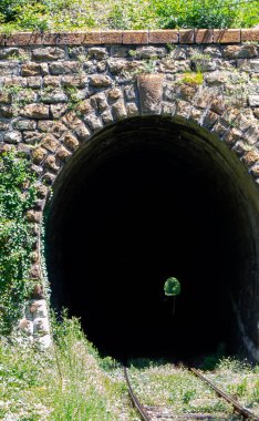 Terk edilmiş bir demiryolu tünelinin ürkütücü görüntüsü. Karanlığı delip geçen ışık, umudu ve yeni başlangıçları simgeliyor..