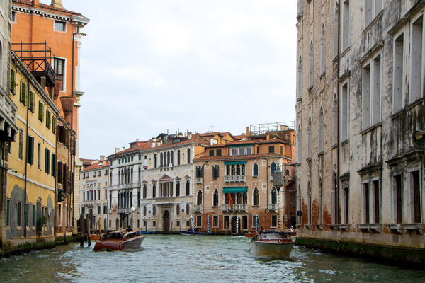 A view of historic Venetian buildings along the Grand Canal, showcasing classic Italian architecture. The iconic canal waters reflect the facades, with boats and gondolas adding to the charm of Venice, Italy famous city of canals.
