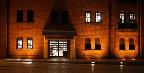 Vista Noturna Edifício Parede Tijolo Iluminado Pela Luz Laranja — Fotografia de Stock