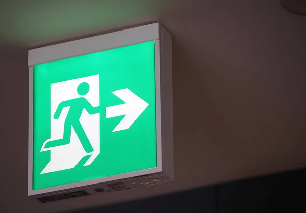 Glowing green emergency exit signs indoors in Japanese buildings