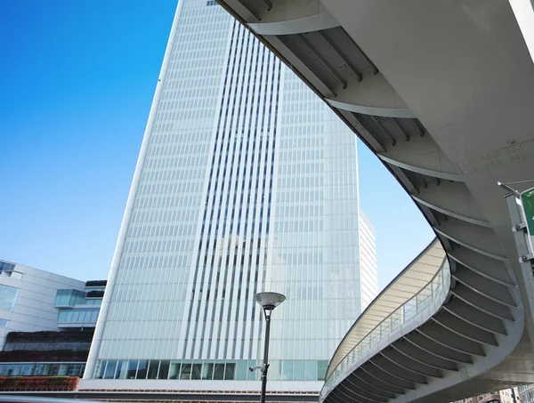 青い空の日に都市の高層ビルや湾曲した歩道橋の建物 — ストック写真