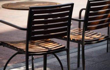 Şehir meydanındaki bir kafede tahta sandalyeler ve masalar.                               