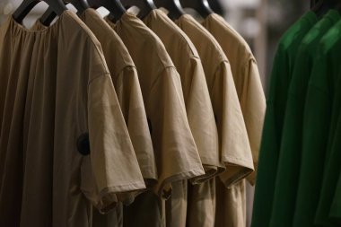 Evin dolabına asılmış pek çok kıyafet zayıf bir ışıkla aydınlatılmış.                               