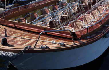 Limanı gezen bir gemide güneşli bir günde rıhtıma yanaşan bir sürü sandalye.                              