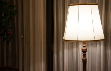 Geceleri odada perdeleri olan pencere kenarındaki masa lambası.                               