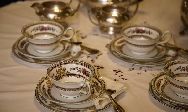 Dinlenme masasında ve masa örtüsünde bir sürü çay fincanı var.                               