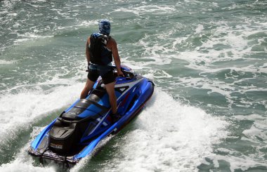 Jet-ski 'de dururken küçük dalgalarda sörf yapan adam..