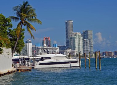 Miami Sahili Sahil İçi Sahili manzarası, küçük bir marinaya yanaşmış lüks Miami Sahili apartman kuleleri ve açık mavi gökyüzü manzaralı bir gökyüzü manzarası..