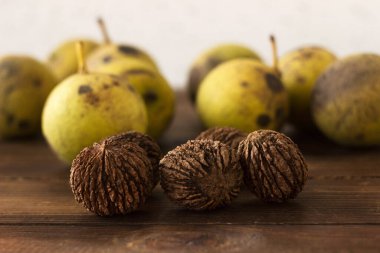 Tahta bir masanın üzerinde siyah ceviz (Juglans nigra) yığını bulunur. Sert kabuklu yararlı fındıklar.