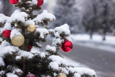 Renkli topları olan bir Noel ağacı yol kenarında, arabaları ve karlı havası olan bir caddede duruyor. Vinnytsia, Ukrayna