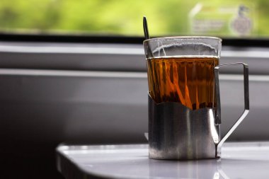 Ukrayna tren vagonunda metal bardak tutacağında bir bardak çay.