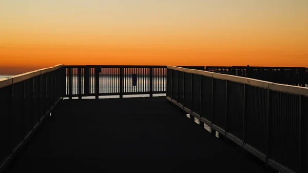 stock image Metal railing silhouette with sunrise colored sky with copy space