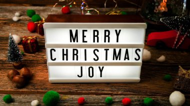 Kırsal ahşap masada Noel dileğiyle aydınlık kutu ve süsler.