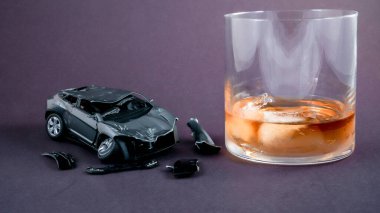 Conceptual car accident with drink in glass on black background