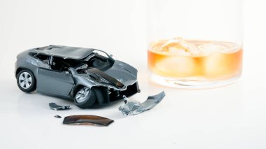 Conceptual car accident with drink in glass on white background