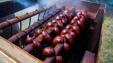 Homemade sausages hanging inside home made smoker outside