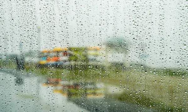 stock image Abstract background from water drops on window with colorful boat in distance