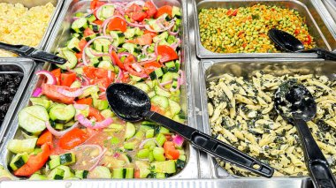 Karışık salata barı ve büyük kaşıklar.