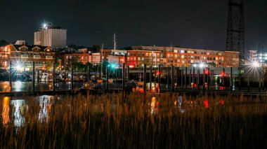 NORWALK, CT, USA- 13 Mayıs 2024 Norwalk gece sahnesi bir Norwalk Nehri 'nin özünü yakalıyor, rıhtımda ışıl ışıl yanan binalar.