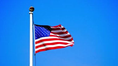 Rüzgarda gururla dalgalanan Amerikan bayrağı açık mavi bir gökyüzünün arka planına karşı