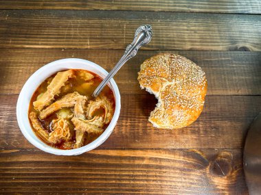 Delicious plate of beef tripe soup with fresh bread on wooden table table top clipart