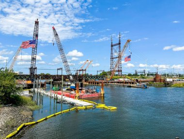 NORWALK, CT, ABD - 30 Ağustos 2024: Güzel bir yaz gününde yeni köprü inşaatında vinçten sarkan Amerikan bayrakları