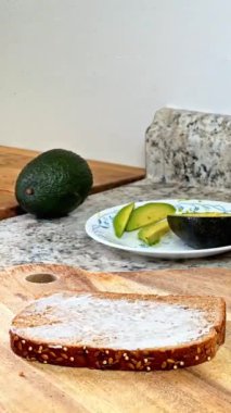 Sıcak mutfak ortamında sağlıklı malzemeler ve taze malzemelerle leziz bir avokado sandviçi hazırlıyorum.