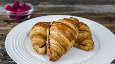 Reçelli üç kruvasanla dolu beyaz bir tabak..