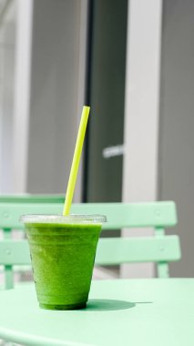 A vibrant green smoothie sits on a pastel green table outside clipart