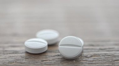 Tahta bir yüzeye yerleştirilmiş beyaz tabletler yuvarlak şekillerini ve ince detaylarını gözler önüne seriyor.