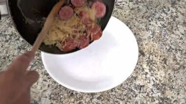 Lezzetli lahana turşusunda servis edilen yumuşak sosis dilimlerinin sunduğu doyurucu yemeğin tadını çıkarın.