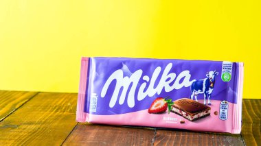 NORWALK, CT USA - JANUARY 12, 2024:   Milka milk chocolate with strawberry on wooden table with yellow background