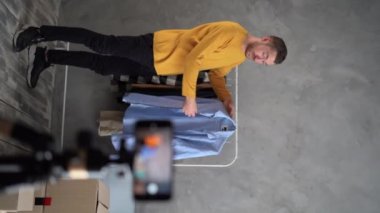 Başarılı Adam akıllı cep telefonu kullanıyor canlı kıyafet satıyor, video blogger kamera kaydediyor küçük işletme sahibi e-ticaret fikirleri kavramını başlatıyor. dikey video