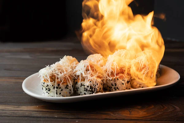 Burned sushi roll. the cook prepares sushi with help of fire and flame