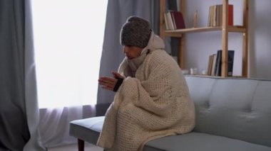 Battaniyeli sağlıksız bir adam soğuk oturma odasında oturur cep telefonu kullanır. Isı ve güç eksikliğinden muzdariptir. Sağlıksız genç adam evdeki dondurucu soğuktan mücadele ediyor. Isıtma kavramı yok.