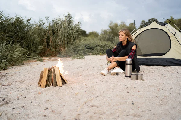 summer camping on sea shore. Woman traveler in the tent and campfire in the evening. Tourism and beauty of nature concept.