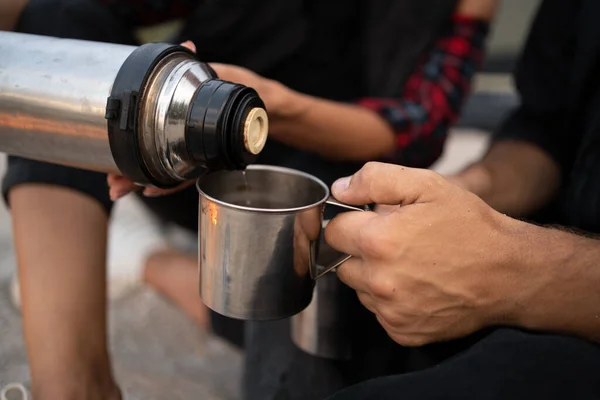 stock image Unrecognizable traveler pouring tea to cup from thermos. Theme tourism and travel. Picnic outdoors. Close up of hands