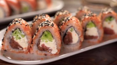 Yemek çubuklarıyla suşi yemek. Suşi restoranda Japon yemeği yuvarlıyor. Somonlu suşi, sebze, havyar, yakın çekim. Japon restoran menüsü konsepti