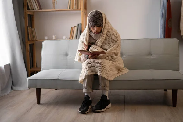 Unhappy man feeling cold wearing warm winter clothes indoors. poor person unable to pay electric bill suffering from cold in own unheated home during winter. Copy space