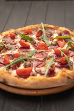 Salamlı pizza, roka ve koyu ahşap arka planda sebzeler. Boşluğu kopyala