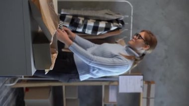 İnternet üzerinden alışveriş yapan işyeri sahibi kadınlar, yerel ofiste ürün paketleme süreci, genç girişimci, KOBİ ve e-ticaret kavramı hazırlıyorlar. Dikey video