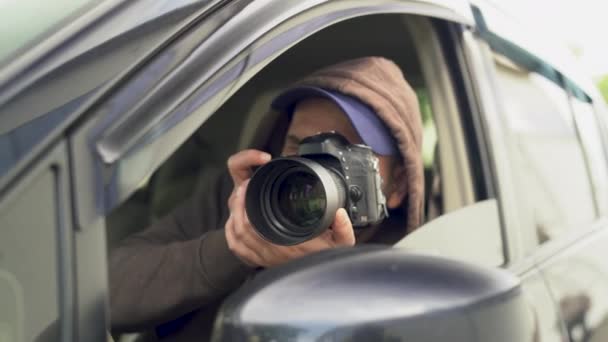 彼の車に座っている間に路上で写真を撮る私立探偵や探偵やパパラッチ — ストック動画