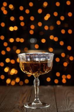 Sert alkollü içki, bardakta konyak. Bulanık ışıkları ve gölgeleri olan ahşap bir arka plan. Kapat.