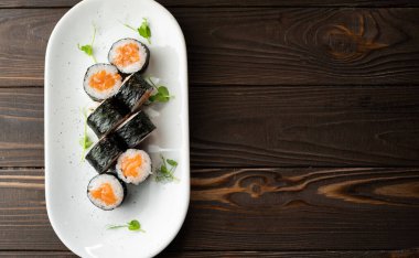 Ahşap zemin üzerinde somon ve peynirli Maki ruloları. Suşi menüsü. Japon gıda konsepti.