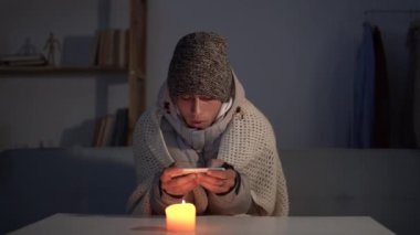 Isıtma ve elektrik kesintisi, genç adamın evinde üşümesi, elektrik kesintisi, elektrik kesintisi, yük boşaltımı. enerji krizi kavramı