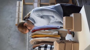 Akıllı telefon üzerinde mobil uygulama kullanan küçük bir kadın işyeri sahibi, elinde telefon tutan online satıcı perakende satış paketini tarayan posta paketi barkodu, cep telefonu teknolojisini işaretleyen paket kutucuğu. Dikey